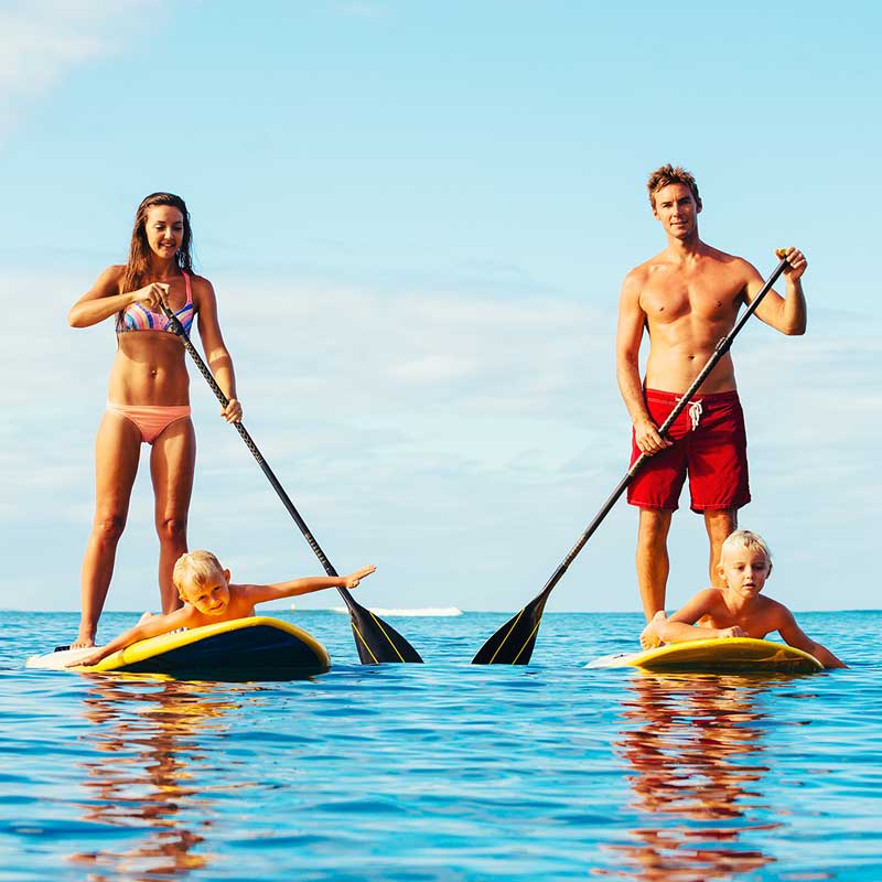 mom and dad on paddle boards with kids on front